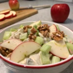 Savourez cette salade de pommes croquantes avec céleri et noix, servie bien fraîche avec une sauce au yaourt onctueuse et relevée de moutarde douce.
