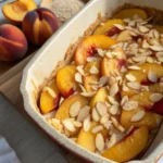 Ce gratin pêches amandes associe des pêches jaunes fondantes et des amandes effilées, servi tiède pour un dessert gourmand et facile à réaliser.