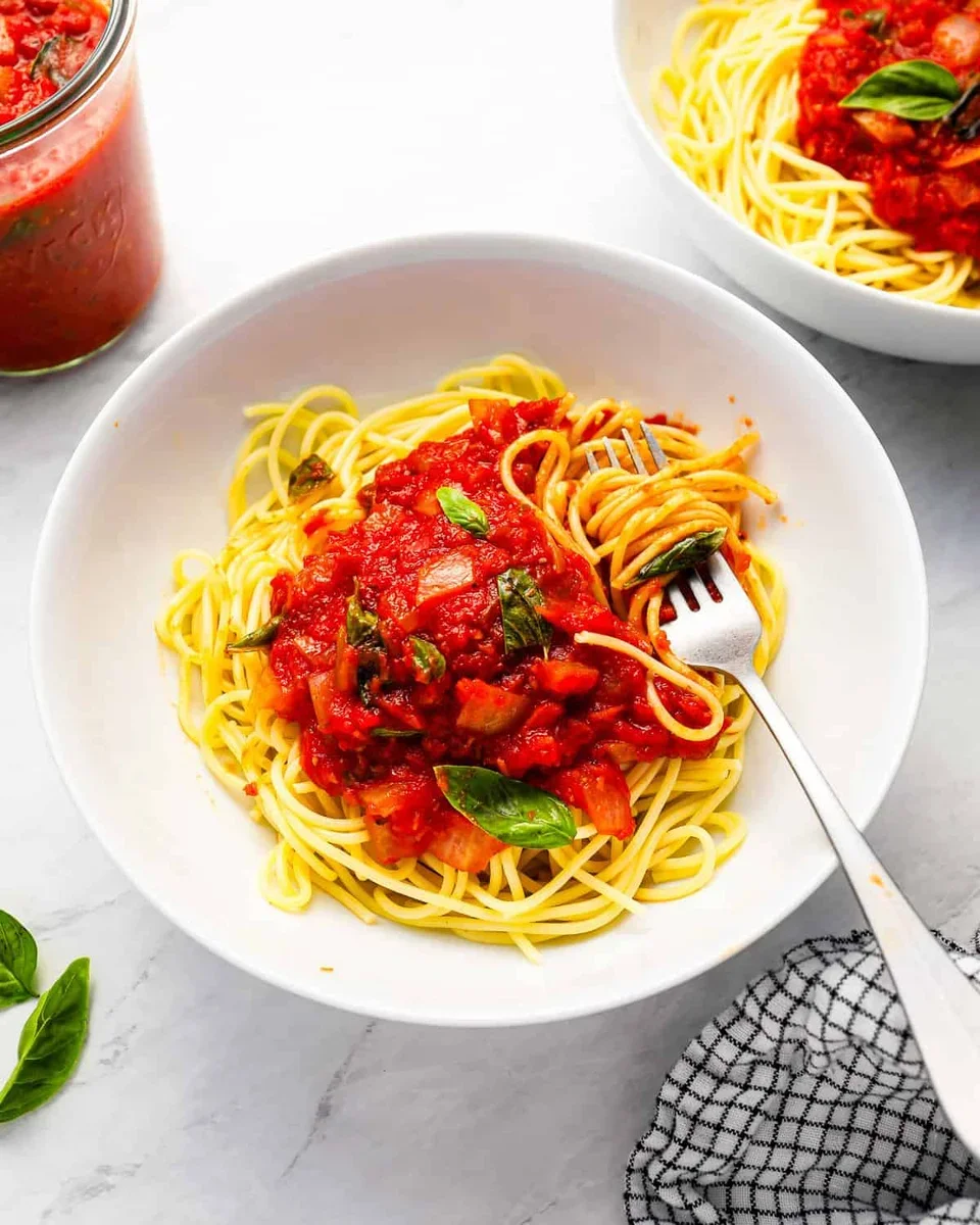 bowl of spaghetti with red sauce and garlic bread on wooden table